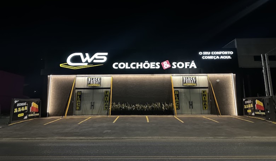 Fachada da loja CWS iluminada à noite, em Guaraituba